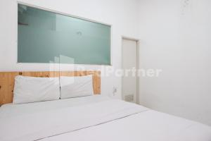 a bedroom with a white bed and a window at Griya Aneka Malioboro Yogyakarta Mitra RedDoorz in Yogyakarta