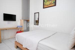 a bedroom with a white bed and a tv at Griya Aneka Malioboro Yogyakarta Mitra RedDoorz in Yogyakarta