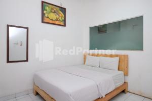 a bedroom with a bed in a white room at Griya Aneka Malioboro Yogyakarta Mitra RedDoorz in Yogyakarta