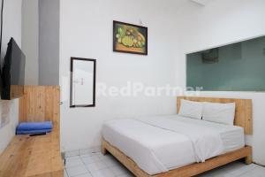 a bedroom with a bed and a flat screen tv at Griya Aneka Malioboro Yogyakarta Mitra RedDoorz in Yogyakarta +16 photos