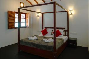 a bedroom with a canopy bed with red pillows at Saachi Lagoon Resort in Kalpitiya
