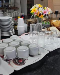 a table with glasses and cups and plates and flowers at Hotel Entre Lagos in São José do Cerrito +57 photos