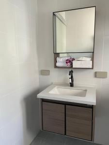 a bathroom with a sink and a mirror and towels at Butterfly Home Mai Khao Phuket in Ban Suan Maphrao