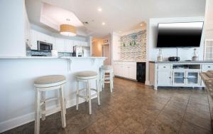 a kitchen with a bar with stools and a tv at Phoenix West 603 in Orange Beach