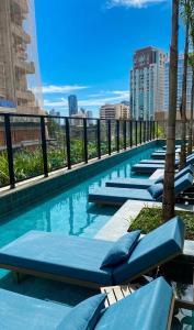 a swimming pool with chaise lounges on a building at Azure Aesse Hospitality Marista in Goiânia