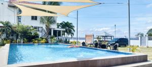 a swimming pool with a umbrella and a car and the ocean at Beachfront Mansion and Seascape Villas Calatagan with Outdoor Pool in Calatagan