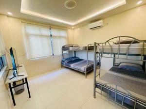 a room with three bunk beds and a television at Camp J Staycation in Cayucay