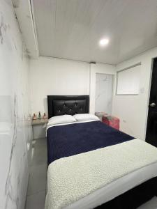 a bedroom with a bed with a blue and white blanket at Apartamento cerca mall plaza in Manizales
