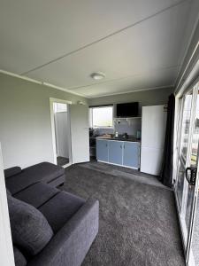 a living room with a couch and a kitchen at Seaview Cabin in Tapu +2 photos