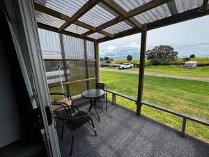 a screened porch with a table and chairs and a field at Seaview Cabin in Tapu