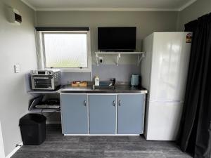 a kitchen with a refrigerator and a sink and a microwave at Seaview Cabin in Tapu