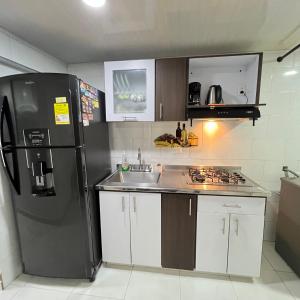 a kitchen with a black refrigerator and a sink at Apartamento cerca mall plaza in Manizales