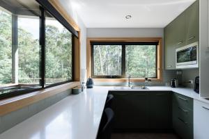 a kitchen with a sink and two windows at Moss Wood Lane: Peaceful Bath Hideaway in Spreyton