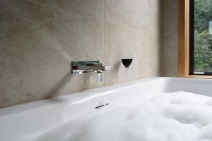 a bath tub with a glass of wine in it at Moss Wood Lane: Peaceful Bath Hideaway in Spreyton +21 photos