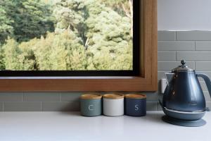 a kitchen counter with a tea kettle and four cups at Moss Wood Lane: Peaceful Bath Hideaway in Spreyton
