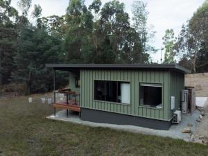 a green tiny house in a yard at Moss Wood Lane: Peaceful Bath Hideaway in Spreyton