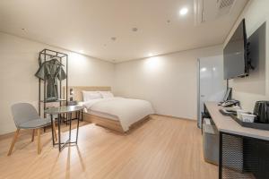 ein Hotelzimmer mit einem Bett, einem Tisch und einem Schreibtisch in der Unterkunft hotel J bay in Samgong-ni