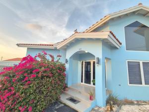 a blue house with flowers in front of it at Villa Sirena Azul Apt 2 in Palm-Eagle Beach