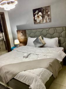 a bedroom with a large white bed with a headboard at Compound Porto New Cairo in Cairo