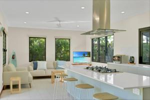 a kitchen with a white counter top and a living room at Balu luxe in Broome