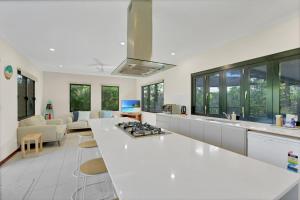 a kitchen with a white counter top and a living room at Balu luxe in Broome