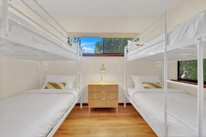 two white bunk beds in a room with a table at Balu luxe in Broome +39 photos