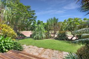 a garden with grass and trees and a wooden bench at Balu luxe in Broome