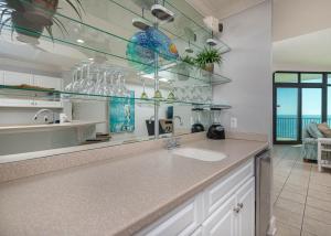 a kitchen with a sink and a counter with glass shelves at Phoenix West 708 in Orange Beach +40 photos