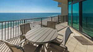 a wooden table and chairs on a balcony with the ocean at Phoenix West 708 in Orange Beach