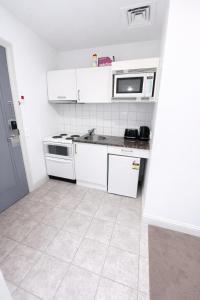 a white kitchen with a sink and a microwave at Sky Tower Studio - Pools, Spa, Gym & Super King in Auckland