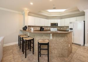 a kitchen with a counter with stools and a refrigerator at Phoenix West 2008 in Orange Beach