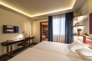 バルセロナにあるヴィンチ マエの白いベッドとデスクが備わるホテルルームです。