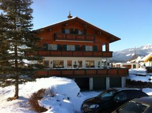 a large wooden house with a car parked in the snow at Pension Köberl in Bad Mitterndorf