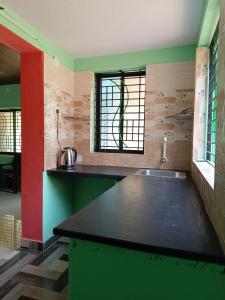 a kitchen with a green counter and a window at Sheshatara Homestay in Honāvar