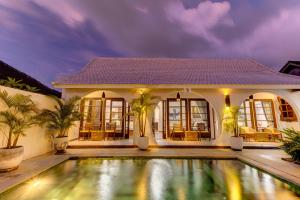 a villa with a swimming pool in front of a house at Olala Suite Canggu Guesthouse in Canggu
