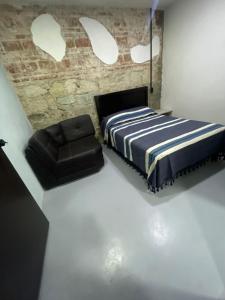 a bedroom with a bed and a leather chair at Casa Rayon Oaxaca in Oaxaca City