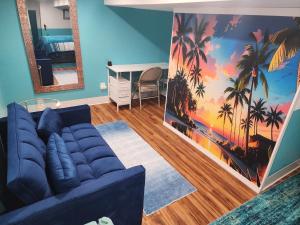 a living room with a blue couch and palm trees mural at Old Salem House 15 mins from downtown Salem in Peabody +12 photos