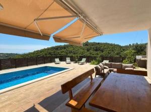 a patio with a pool and a table and an umbrella at Villa Coral in Novo Selo
