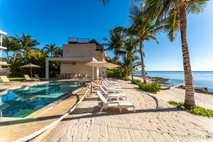 a resort pool with chairs and umbrellas on the beach at EEB TI KAAN TULUM - Luxury Oceanfront Residences in Tulum