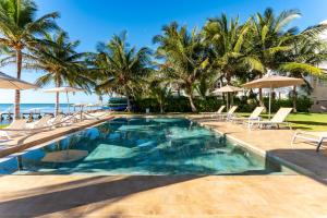 a pool with chairs and palm trees and the ocean at EEB TI KAAN TULUM - Luxury Oceanfront Residences in Tulum