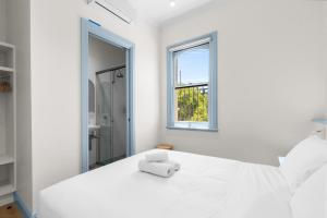 a white bedroom with a white bed and a window at The Surrey 6 in Sydney
