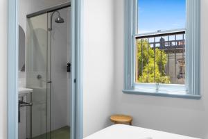 a white bathroom with a window and a shower at The Surrey 6 in Sydney