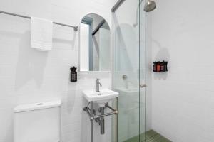 a white bathroom with a sink and a shower at The Surrey 6 in Sydney