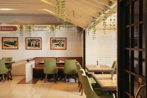 a restaurant with wooden tables and green chairs at Impiana Hotel Ipoh in Ipoh