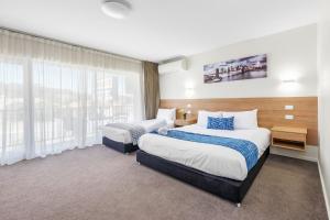 a hotel room with two beds and a window at Rainbow Motel Queanbeyan in Queanbeyan