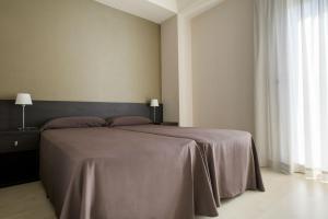 - une chambre avec un grand lit et une couverture grise dans l'établissement Residencia Universitaria Damia Bonet, à Valence