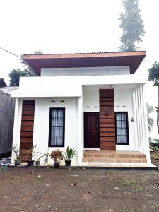 a white house with a brown and white facade at Griya Alborz Dieng in Garung