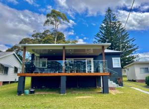 a house with a deck on the front of it at Barefoot and Beach Bound by Book Jervis Bay in Vincentia