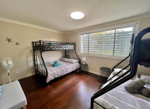 a bedroom with two bunk beds and a window at Barefoot and Beach Bound by Book Jervis Bay in Vincentia
