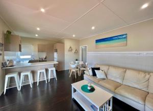 a living room with a couch and a kitchen at Barefoot and Beach Bound by Book Jervis Bay in Vincentia